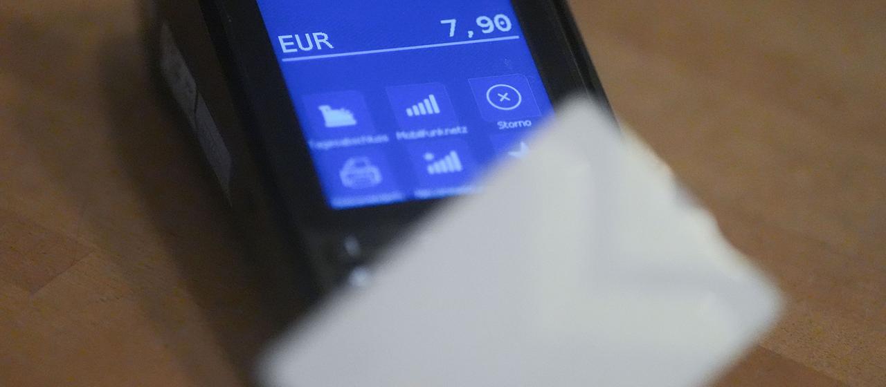 Ein Mann hält seine Debitkarte an ein Lesegerät an der Kasse.