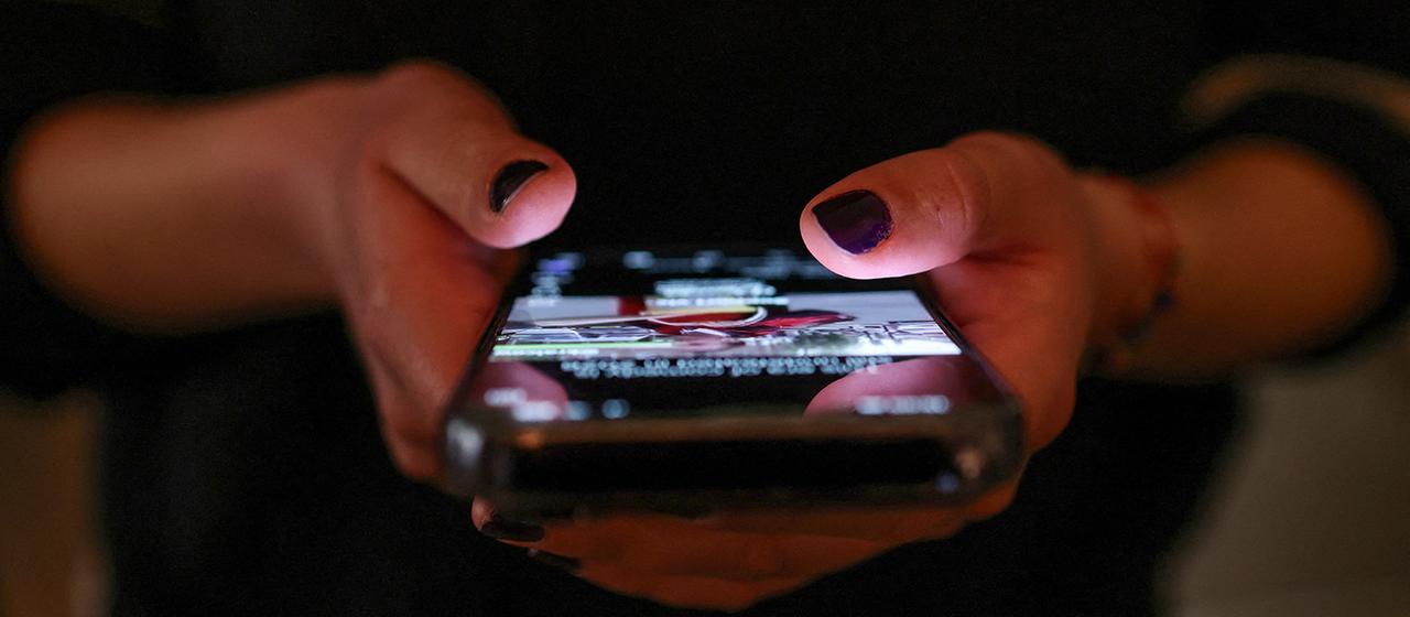 A girl checks social media posts on her cell phone.