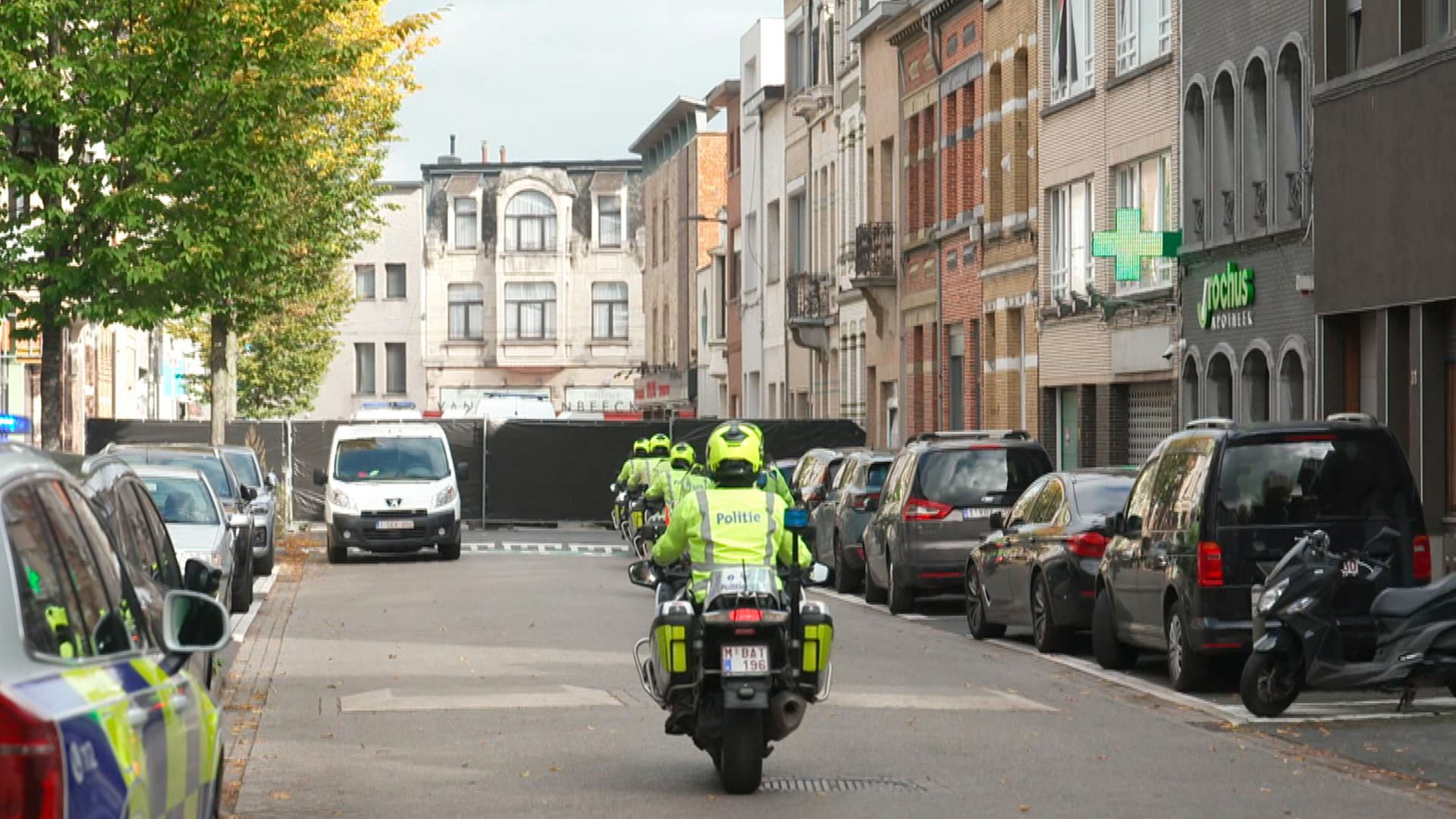Polizisten auf Motorrädern fahren auf eine schwarze Polizeisperre zu, die in Antwerpen wegen Terrorermittlungen errichtet wurde. | dpa