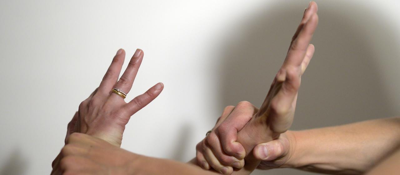 Männerhände greifen mit Gewalt Frauenhände.