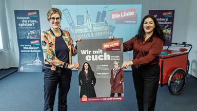 Heike Sudmann (l.) und Cansu Özdemir, Spitzenkandidatinnen der Partei Die Linke, präsentieren die Plakat-Kampagne der Linken zur Bürgerschaftswahl in Hamburg.