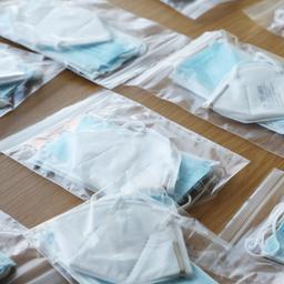 Mehere Schutzmasken und OP-Masken liegen verpackt auf einem Tisch.