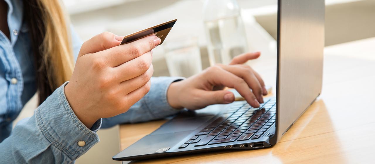 Eine Frau tippt die Nummer ihrer Kreditkarte auf einem Laptop.