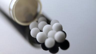 Aus einem Röhrchen geschüttete homöopathische Globuli.