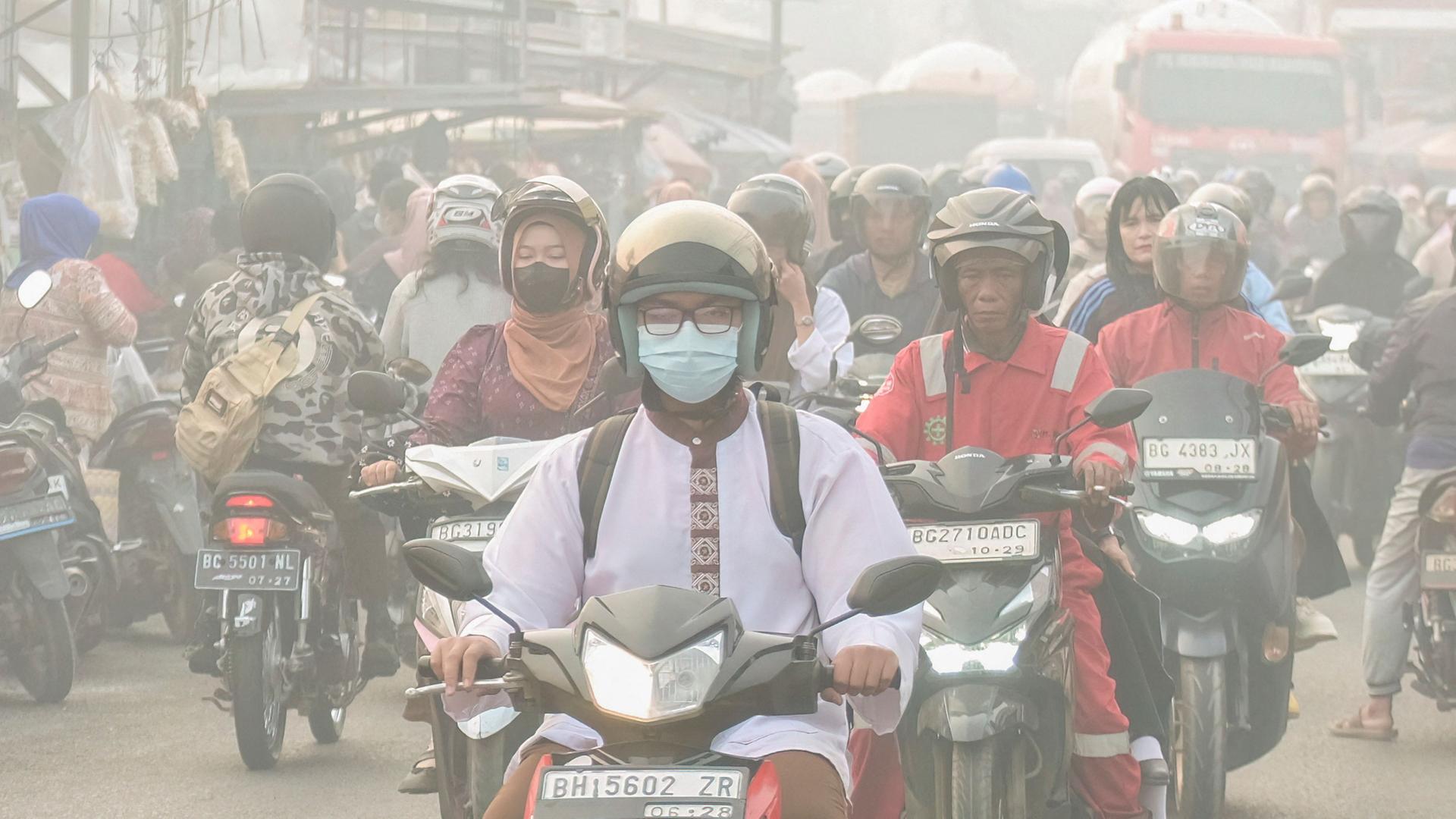 Menschen sind auf einer StraÃe unterwegs, wÃ¤hrend Palembang in SÃ¼d-Sumatra von Rauch aus Wald- und FlÃ¤chenbrÃ¤nden eingehÃ¼llt ist. | AFP