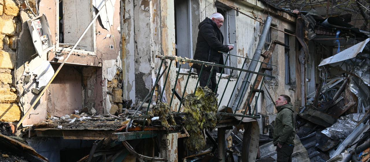 Menschen stehen vor den Trümmern eines Hauses in Odessa.