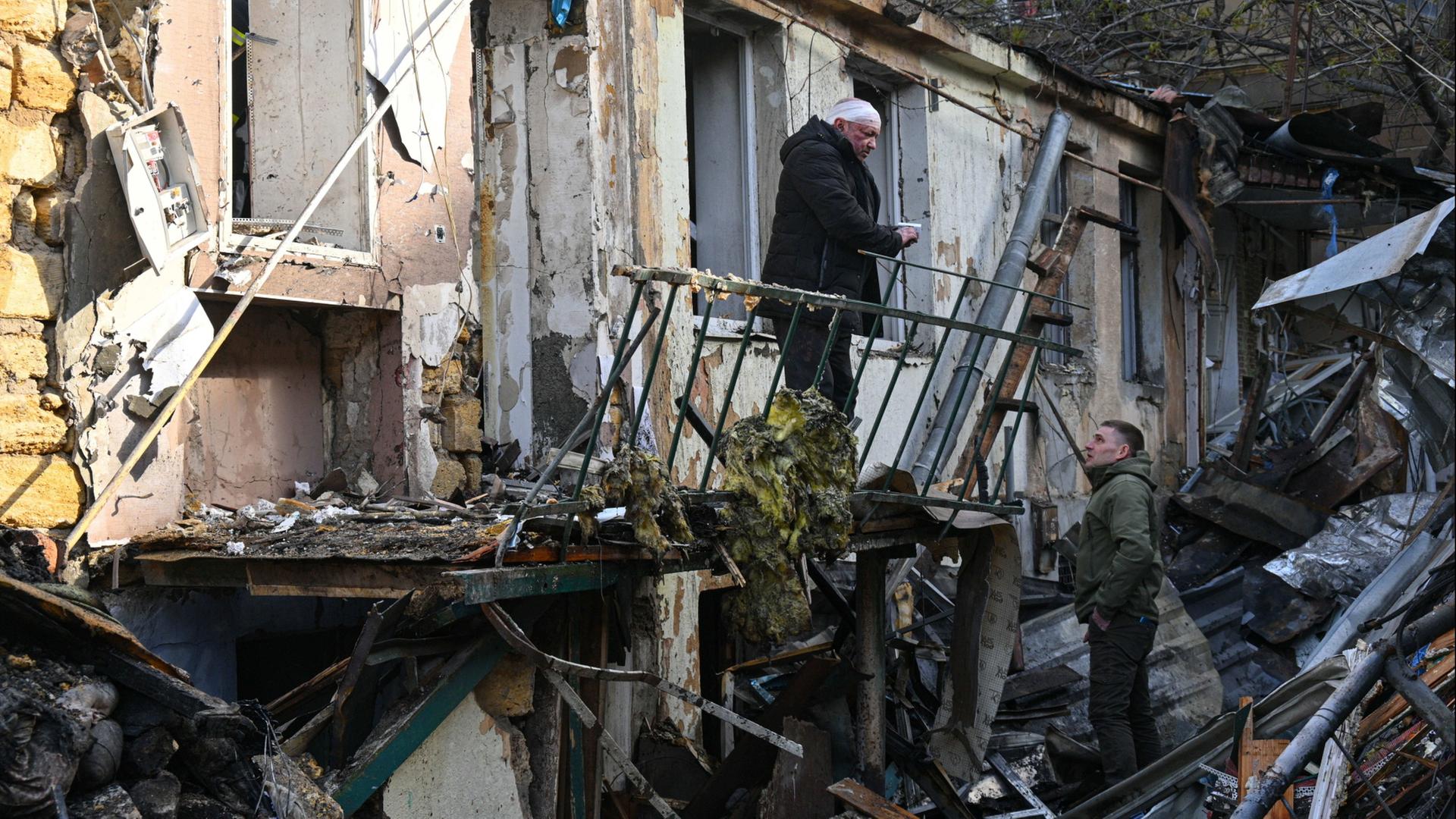 Menschen stehen vor den Trümmern eines Hauses in Odessa. | AP Photo/Michael Shtekel
