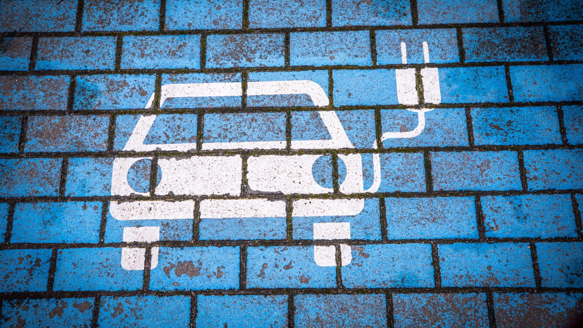 Ein Aufdruck auf StraÃenpflaster zeigt ein Elektroauto mit einem Ladekabel. | dpa