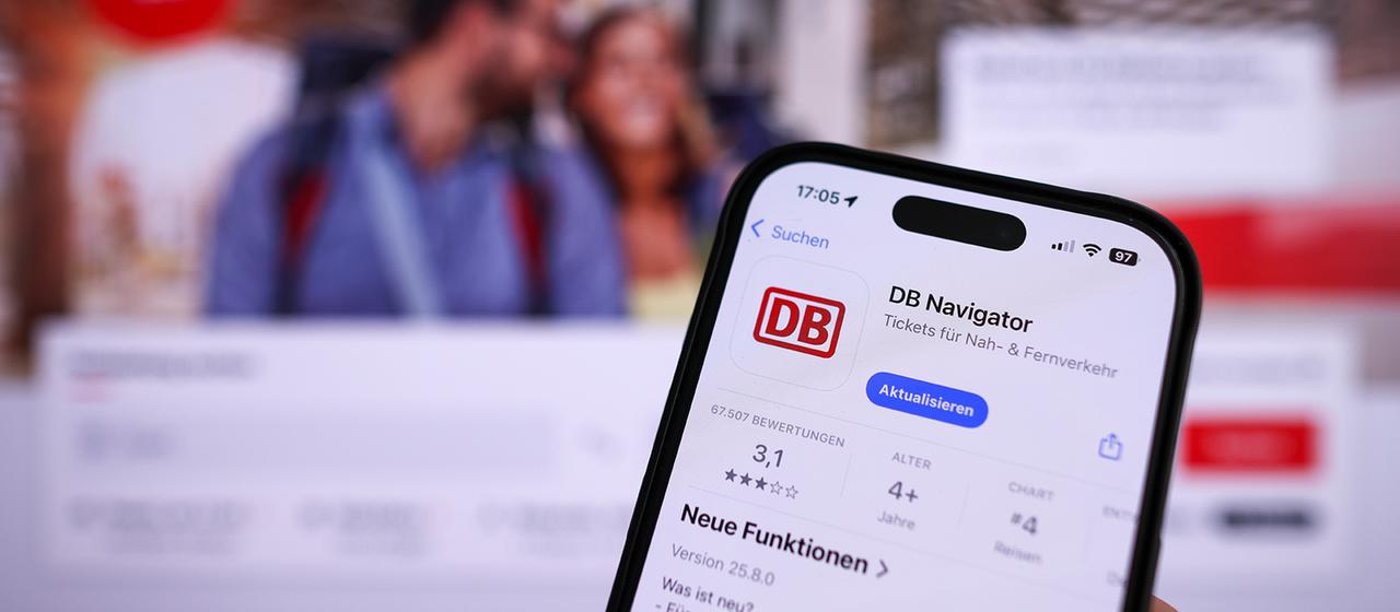 Eine Hand hält ein Mobiltelefon mit der App DB-Navigator im App-Store.