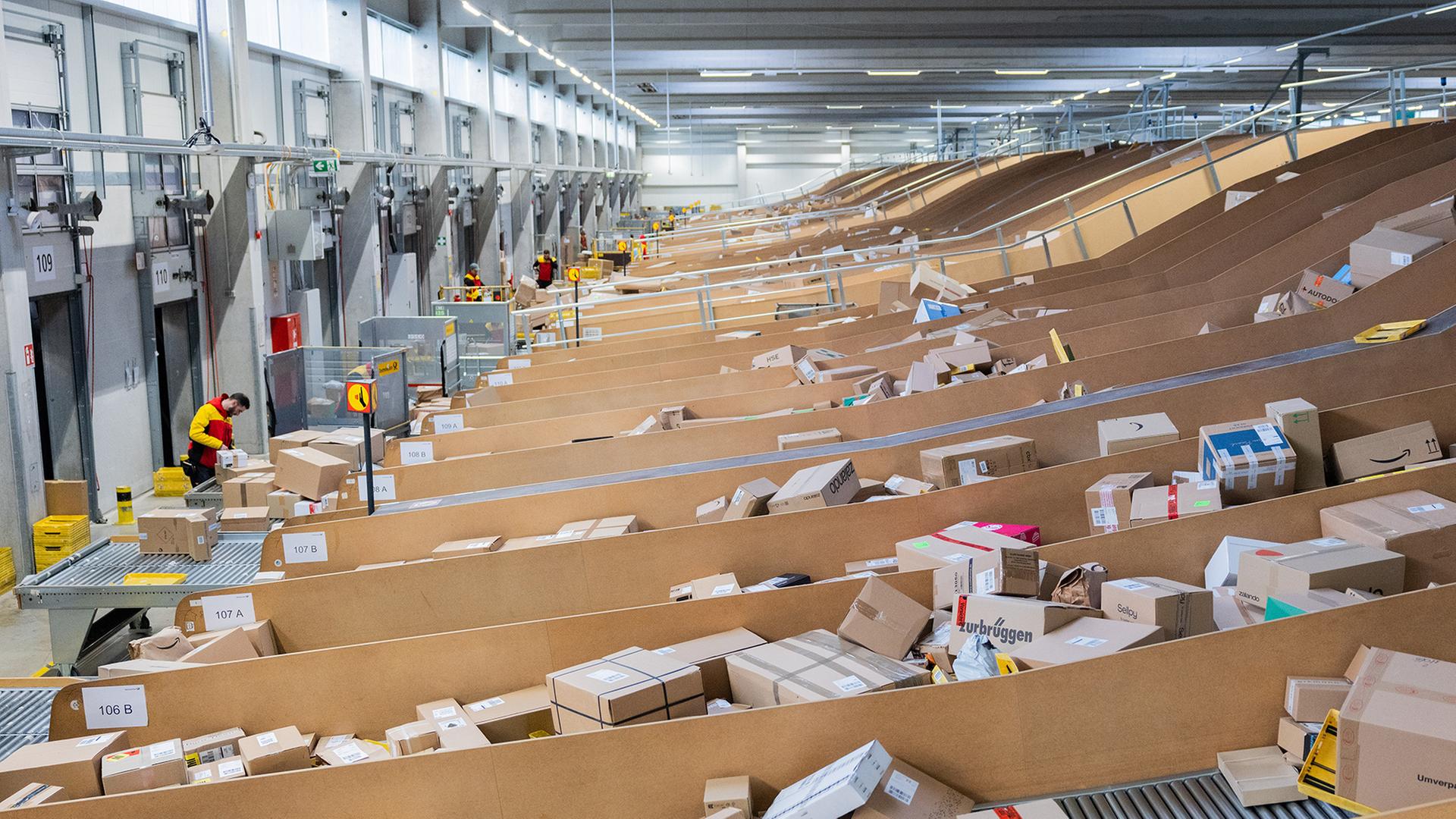 Paketzusteller sortieren und räumen in einer Zustellbasis von Deutsche Post DHL Pakete in Zustellfahrzeuge. | picture alliance/dpa