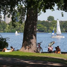 Passanten genießen das Sommerwetter an der Außenalster in Hamburg.