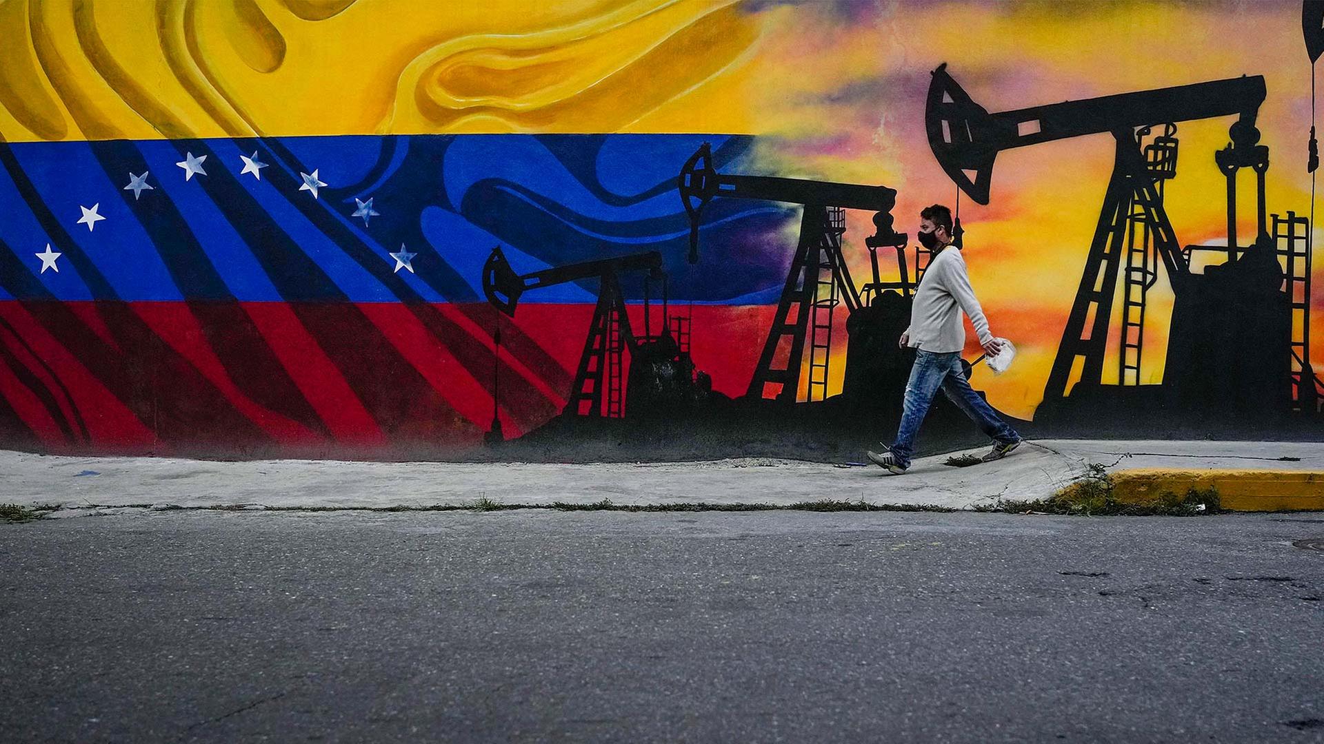 Ein Mann vor einem Wandgem�lde mit �lpumpen und der Flagge Venezuelas. | picture alliance / ASSOCIATED PR