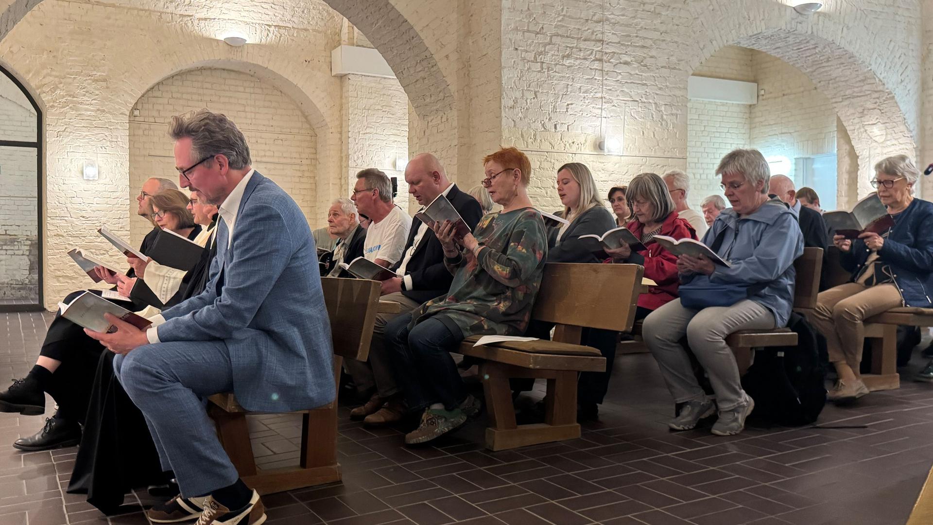 Eine Gruppe von Menschen sitzen im Gottesdienst und halten ihre Gesangsbücher in der Hand | WDR/ Maike Krebber