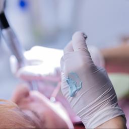 Ein Zahnarzt führt eine Zahnreinigung bei einem Patienten durch.