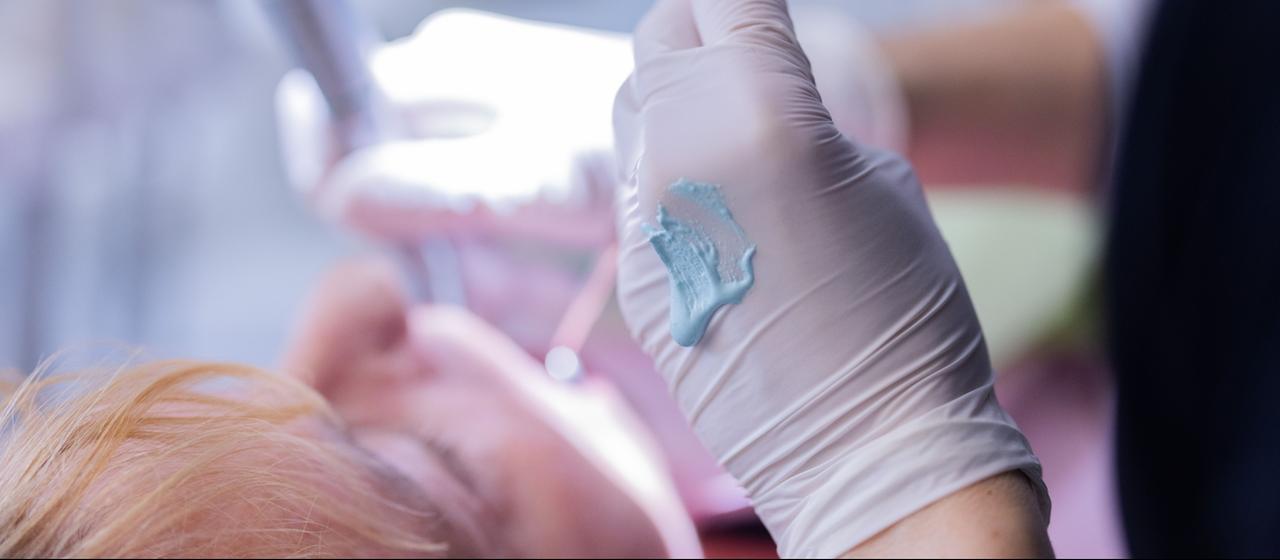 Ein Zahnarzt führt eine Zahnreinigung bei einem Patienten durch.