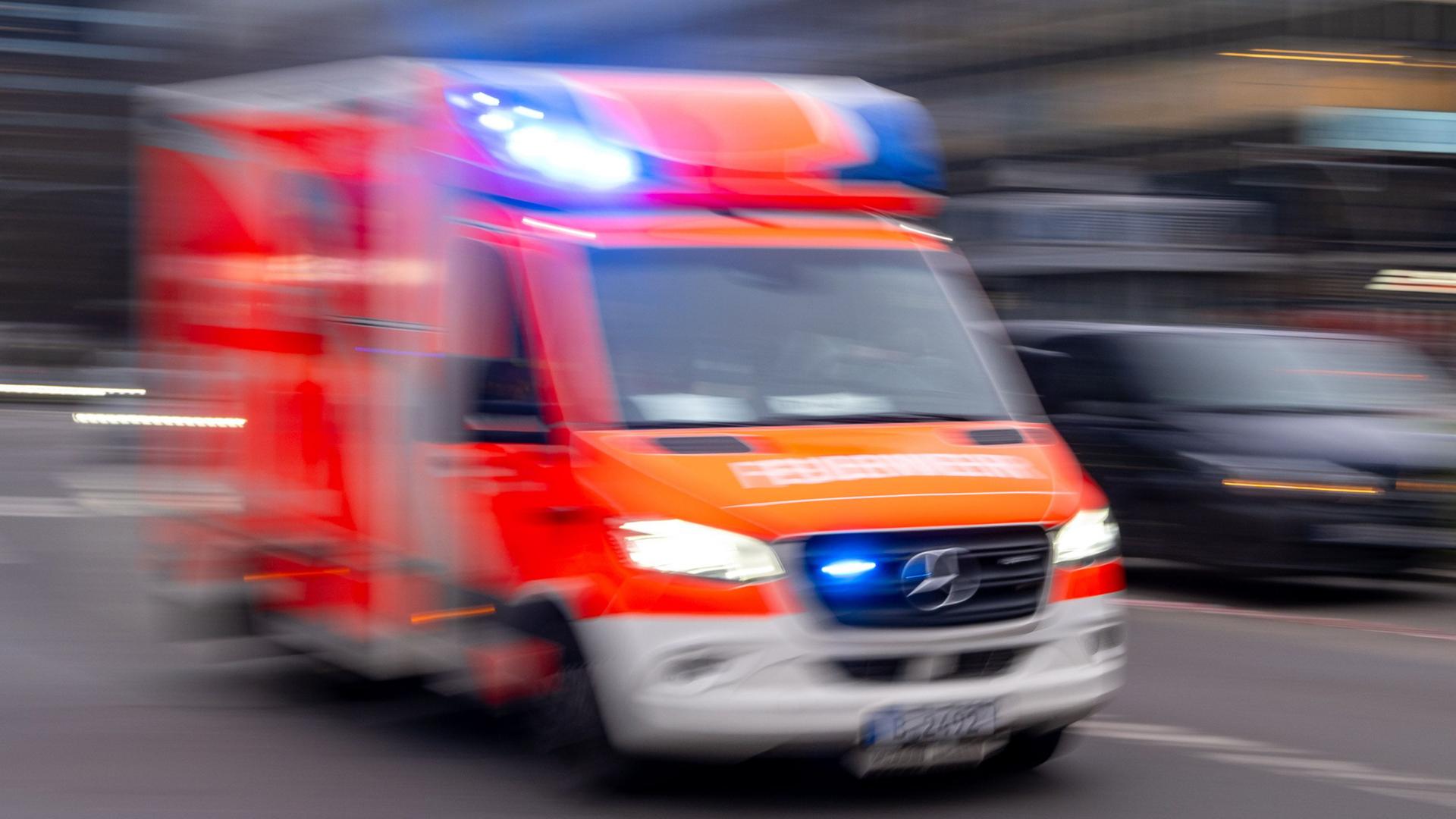Schemenhaft sieht man einen Rettungswagen der Feuerwehr auf einer Straße fahren. | Monika Skolimowska/dpa