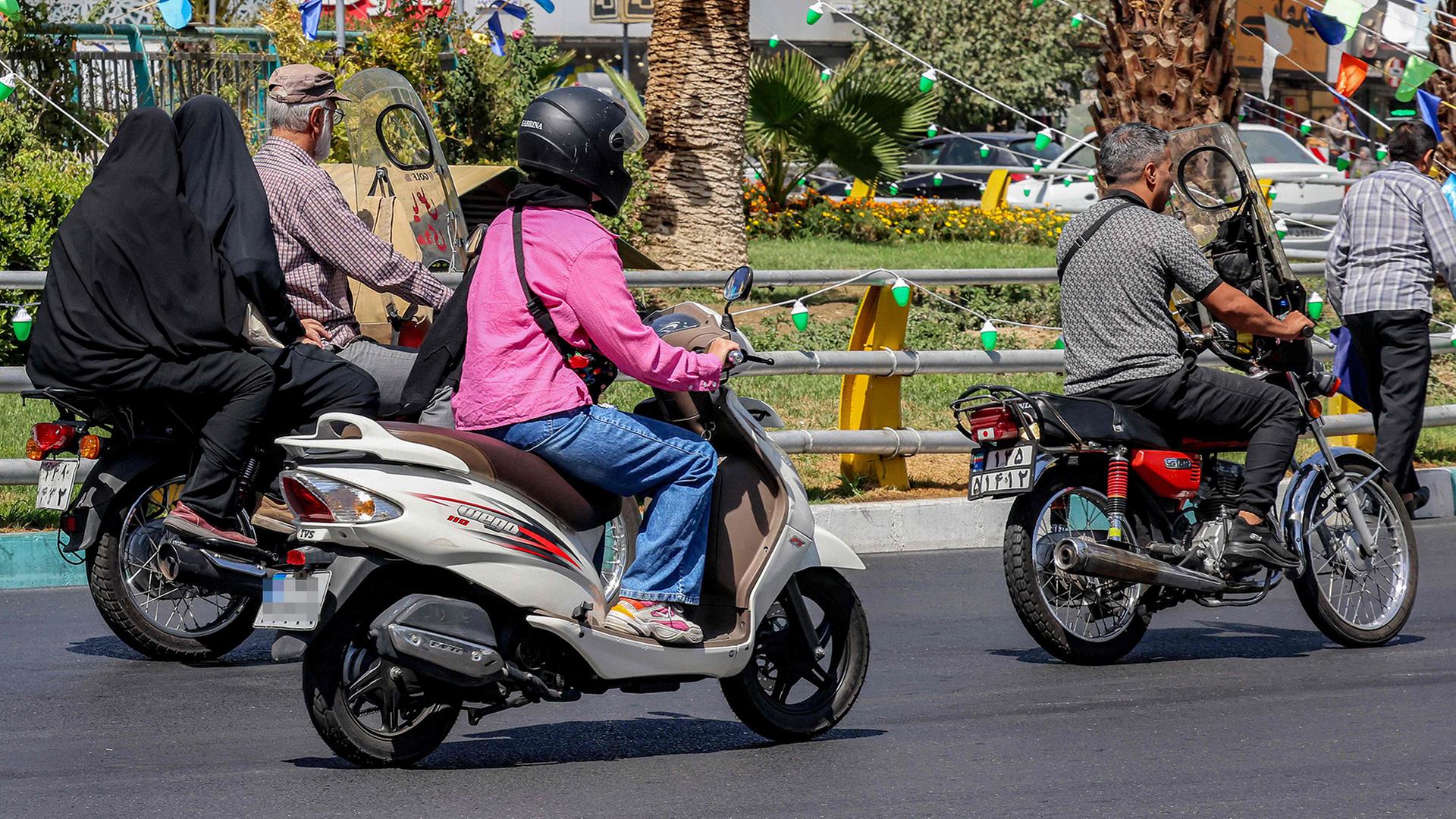 Frauen und Männer auf Motorrollern auf einer Straße in Teheran, Iran. | AFP