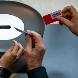 Hände mit Abstimmungskarten an einer Urne im Bundestag