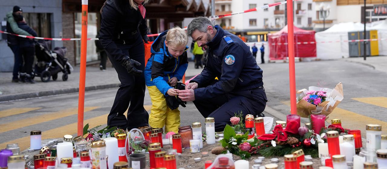 Ein Polizist hilft einem Jungen beim Anzünden einer Kerze in der Nähe der Bar 