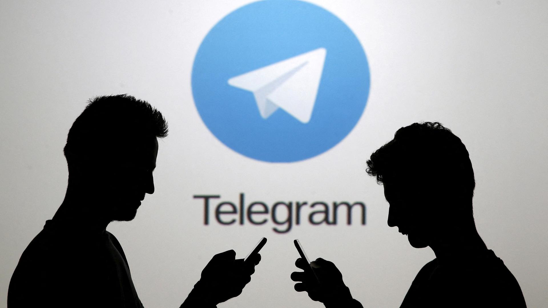 Zwei M�nner posieren mit Smartphones vor einem Bildschirm, auf dem das Telegram-Logo zu sehen ist. | REUTERS