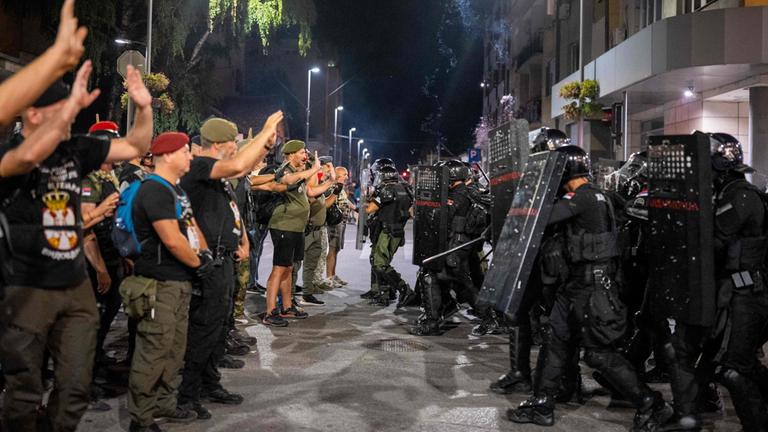 Demonstranten stehen Polizisten in Schutzausrüstung gegenüber.
