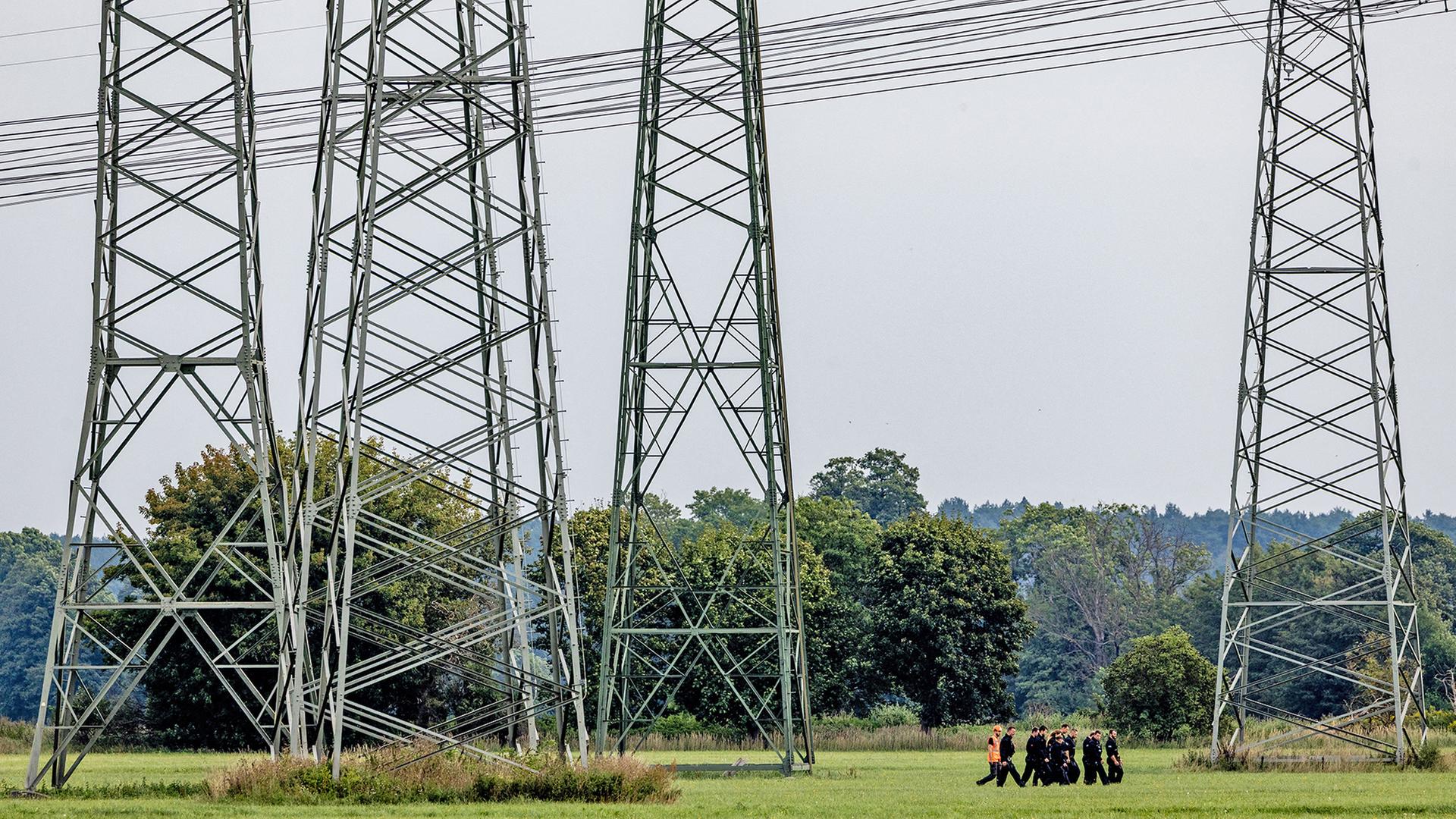 Polizisten durchsuchen im September 2026 den Bereich um Höchstspannungsleitungen um das Umspannwerk Turnow-Preilack (Quelle: Picture Alliance/Frank Hammerschmidt) | Picture Alliance/Frank Hammerschmidt