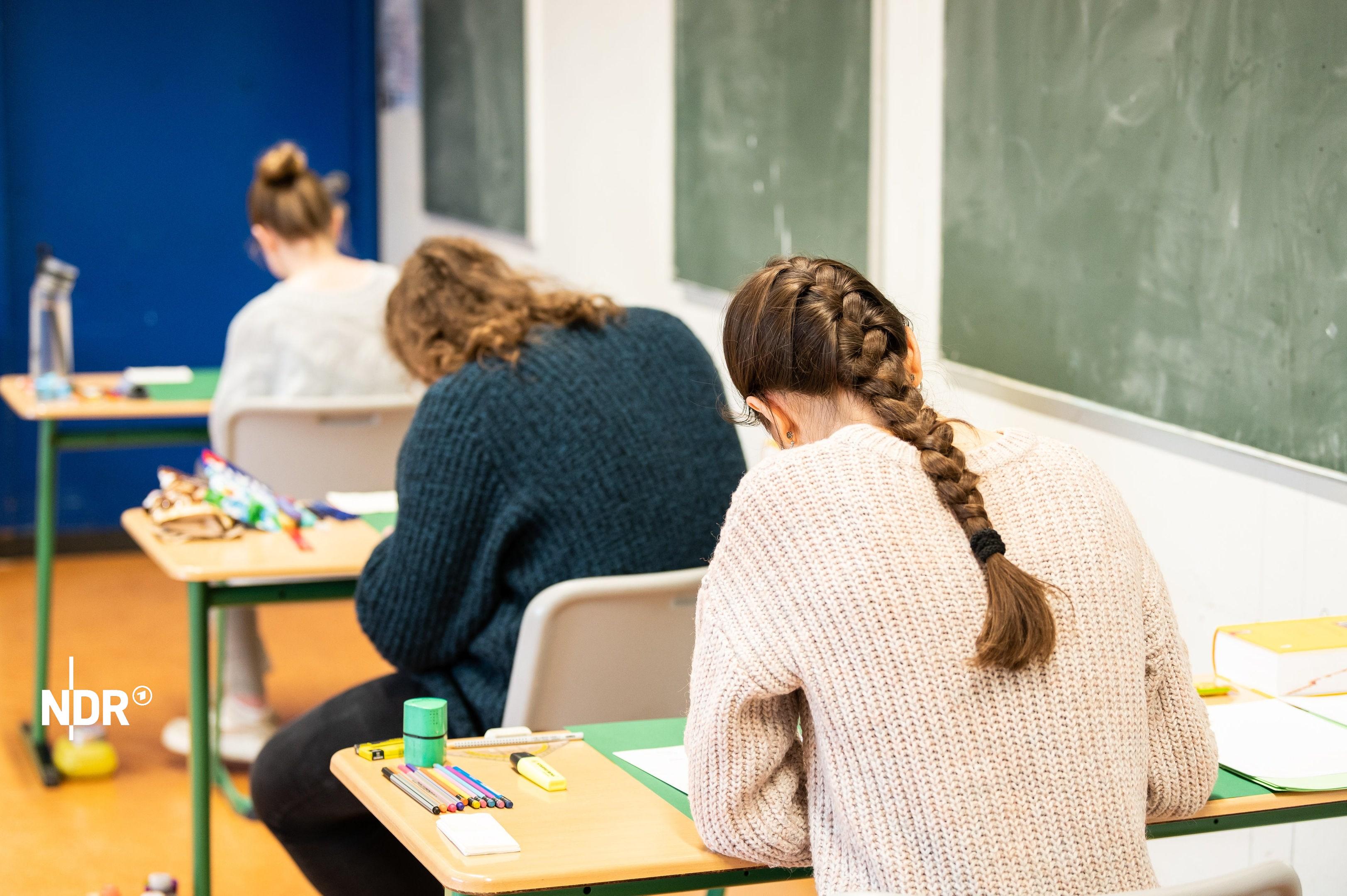 Schülerinnen sitzen während einer schriftlichen Prüfung an Einzeltischen. | picture alliance/dpa Schülerinnen sitzen während einer schriftlichen Prüfung an Einzeltischen.