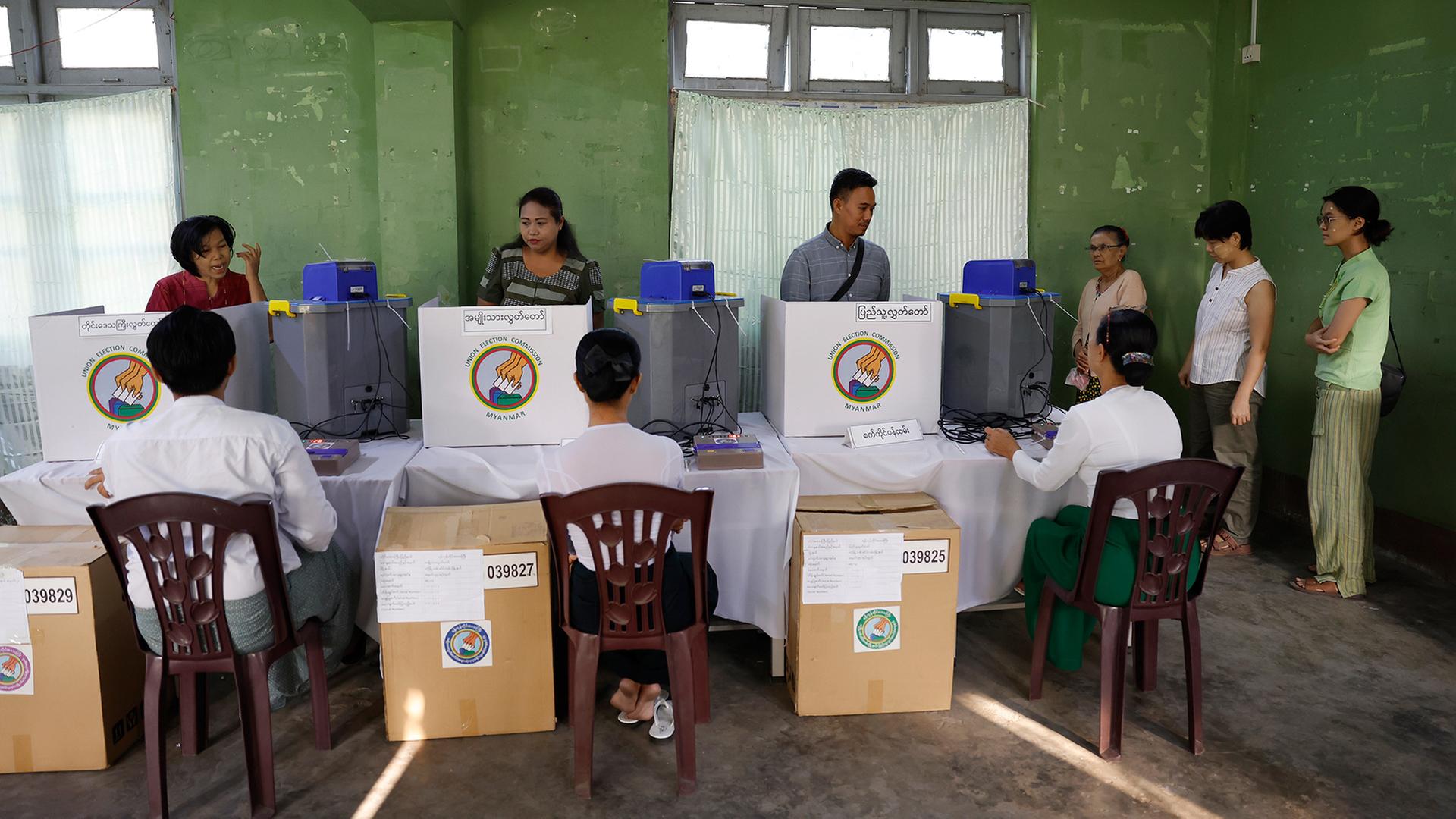 Wähler geben in einem Wahllokal in Myanmar ihre Stimmen mit elektronischen Wahlmaschinen ab. | EPA