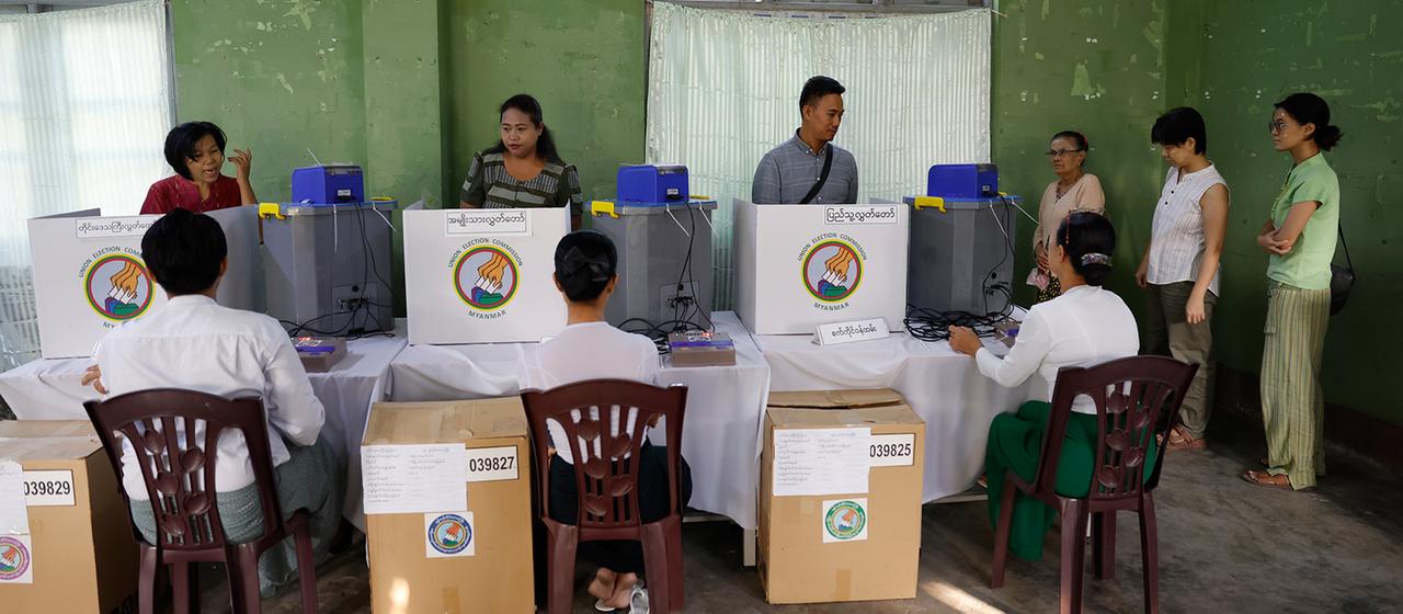 Wähler geben in einem Wahllokal in Myanmar ihre Stimmen mit elektronischen Wahlmaschinen ab.