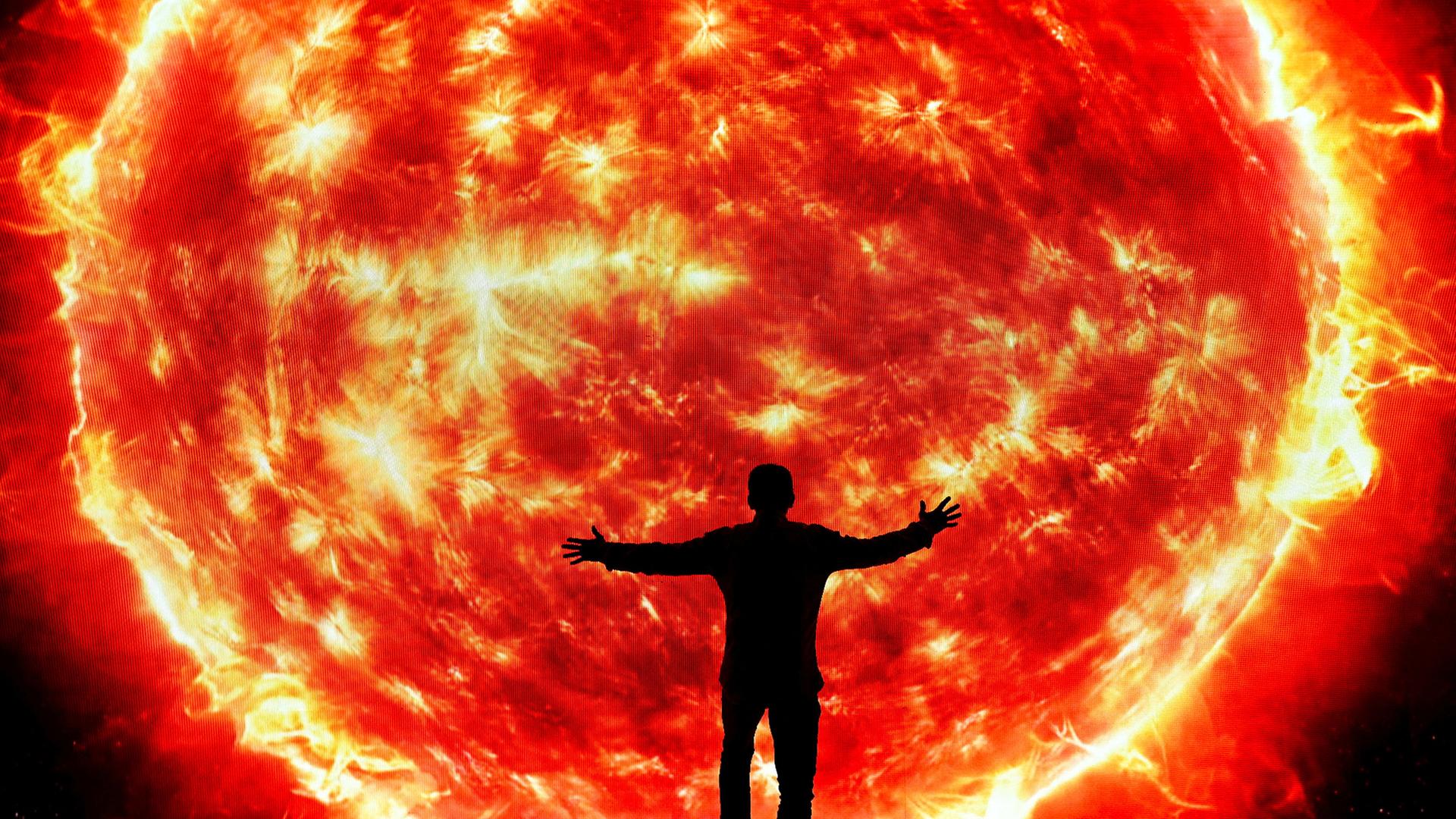 Ein Mann steht mit offenen Armen vor einer projizierten Sonne. | REUTERS