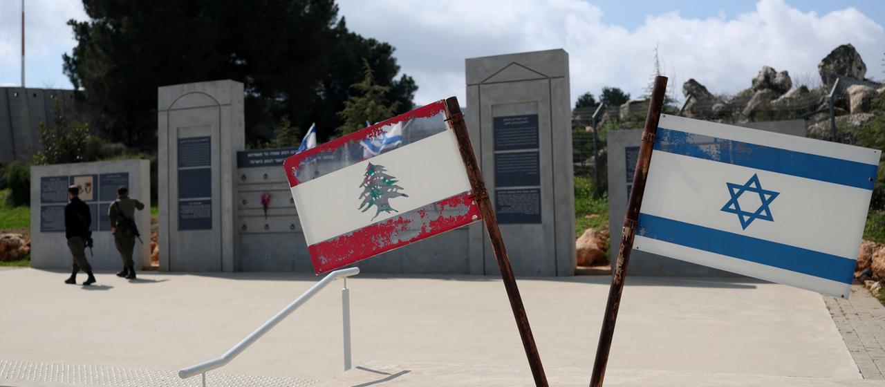 Israelische Soldaten stehen in der Grenzstadt Metula neben einem Denkmal, das die israelische und die libanesische Flagge zeigt.