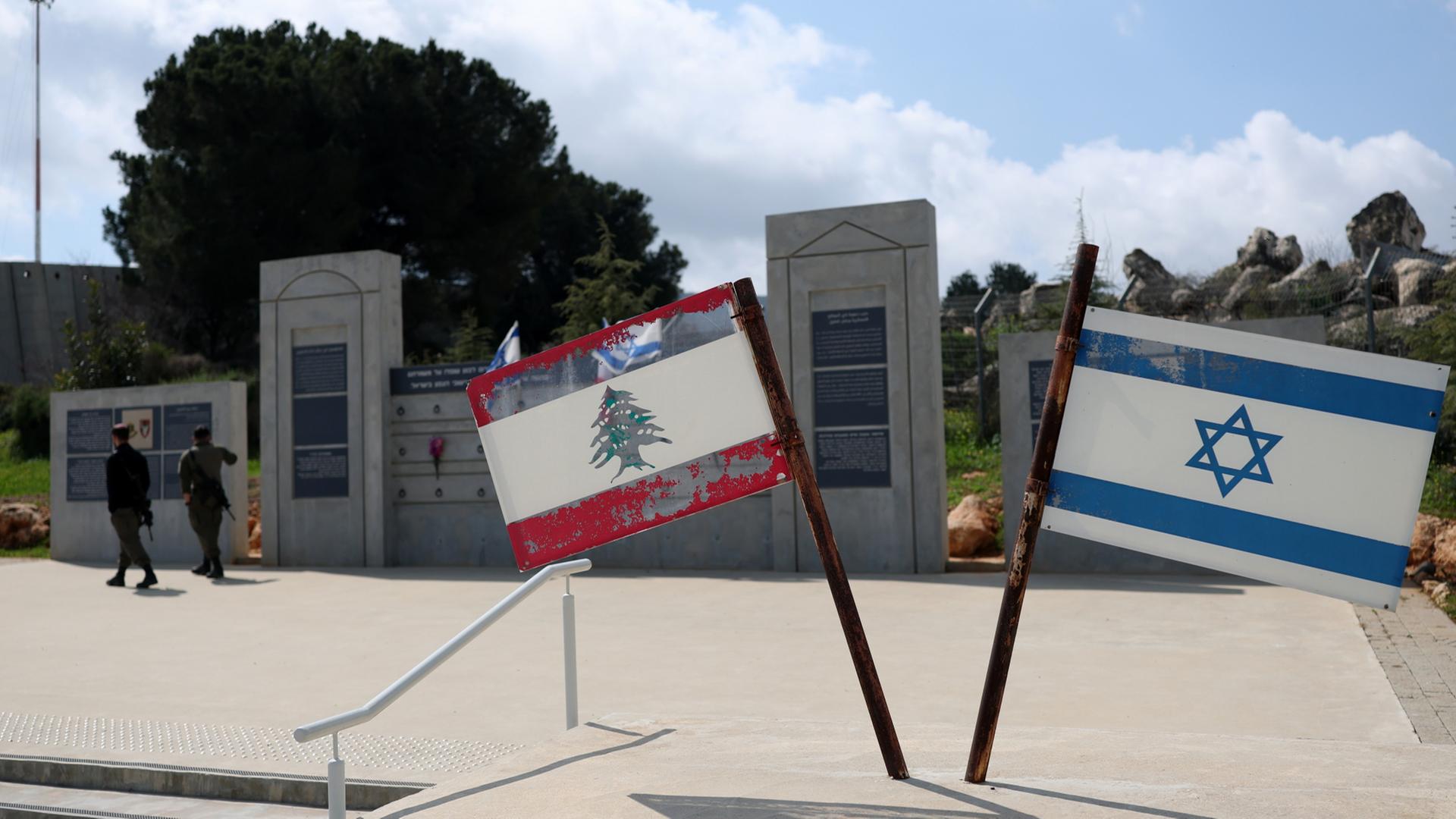 Israelische Soldaten stehen in der Grenzstadt Metula neben einem Denkmal, das die israelische und die libanesische Flagge zeigt. | EPA