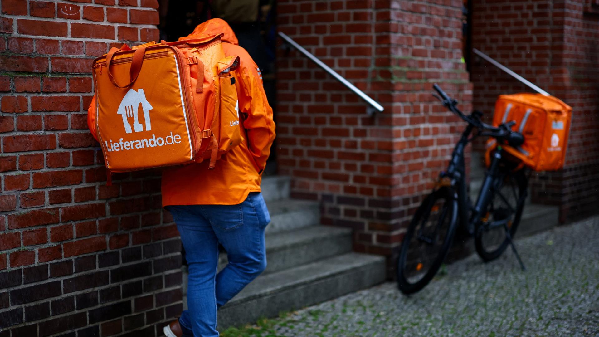 Ein Lieferando-Lieferdienstfahrer steht vor einem Haus in Berlin | REUTERS