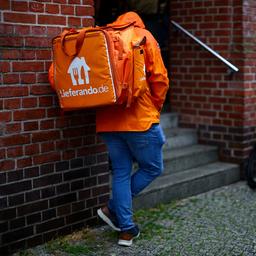 Ein Lieferando-Lieferdienstfahrer steht vor einem Haus in Berlin