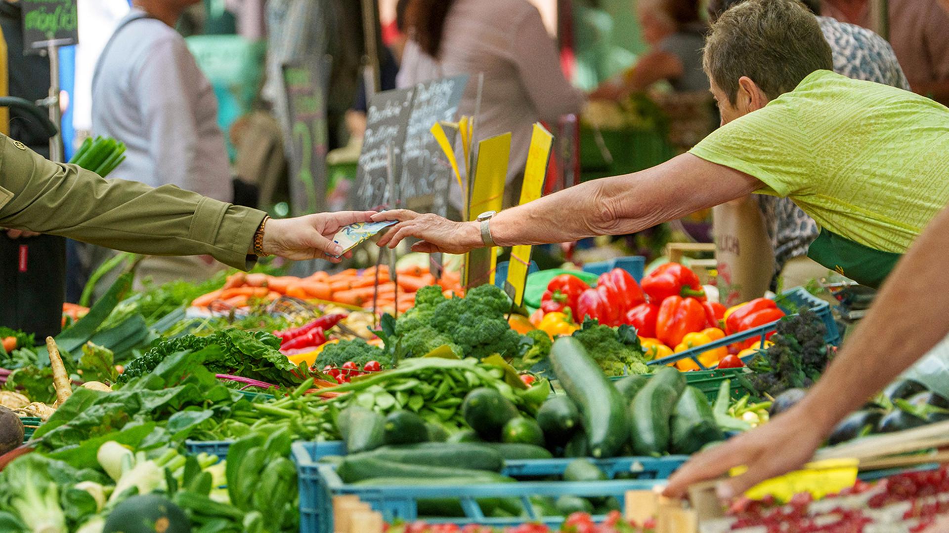 Auf einem Wochenmarkt wird ein Einkauf bezahlt. | dpa
