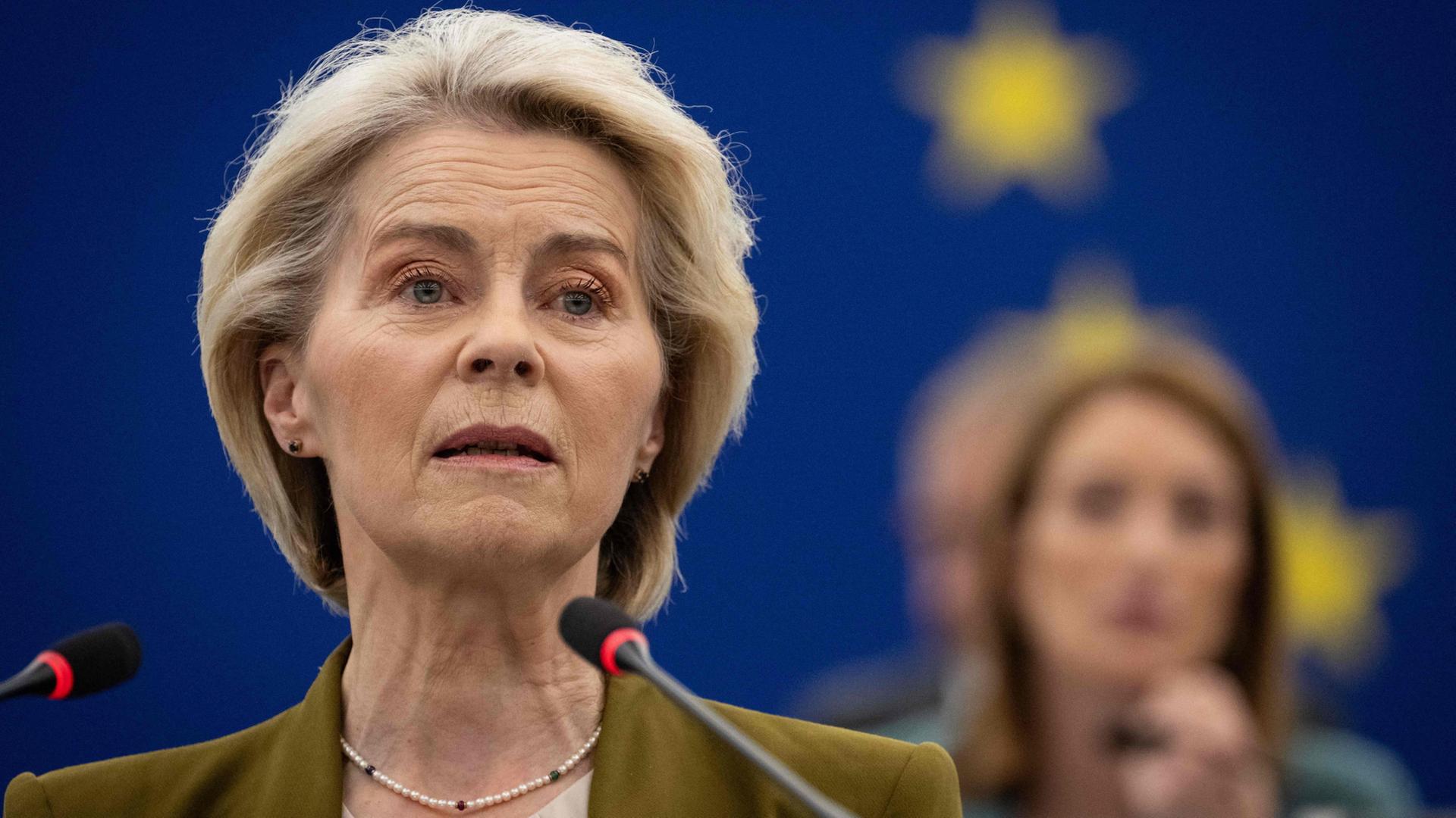Ursula von der Leyen spicht in zwei Mikrofone. | AFP