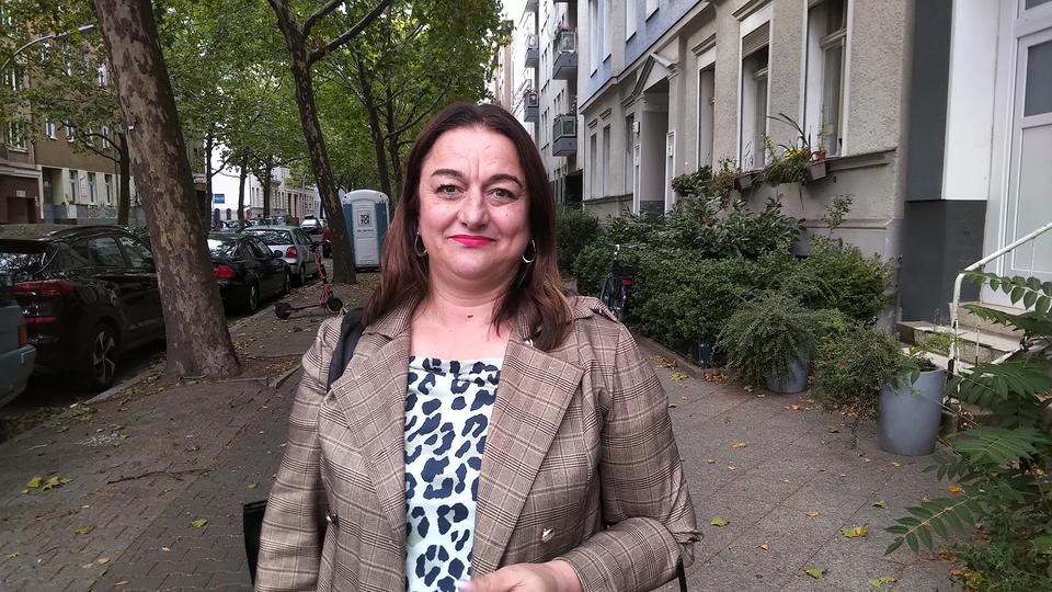 Branka Schmidt suchte lange nach einem Zuhause für sich und ihre Kinder. | Andre Kartschall Branka Schmidt steht auf einem Bürgersteig zwischen Häusern, Autos und Bäumen.