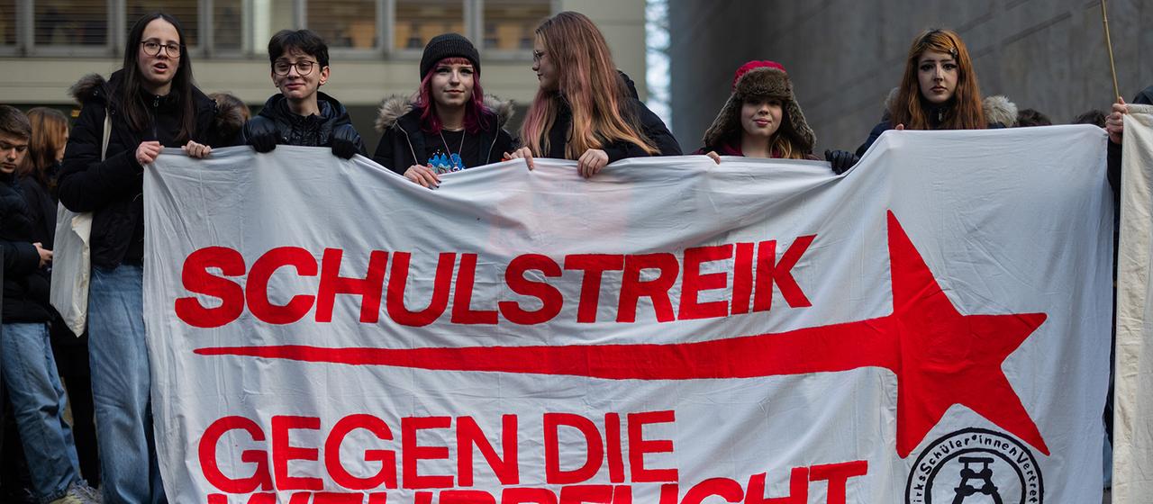 Menschen demonstrieren vor dem Burggymnasium gegen ein mögliches Wehrdienstgesetz.