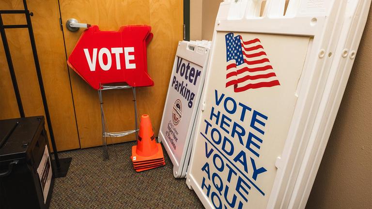 Schilder mit der Aufforderung an US-Bürger Wählen zu gehen stehen in einem Raum bereit.