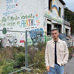 Mann steht vor einem bemalten, aber zerstörten Haus im Ahrtal für die 360-Grad-Reportage.