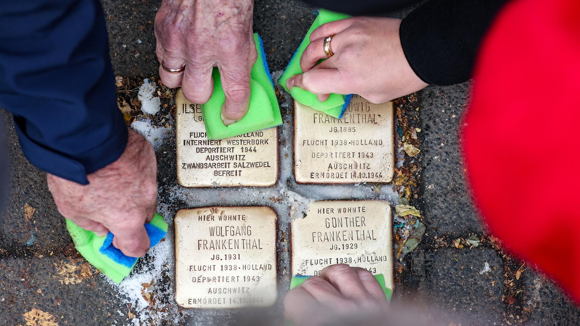 Menschen putzen vier Stolpersteine. | dpa