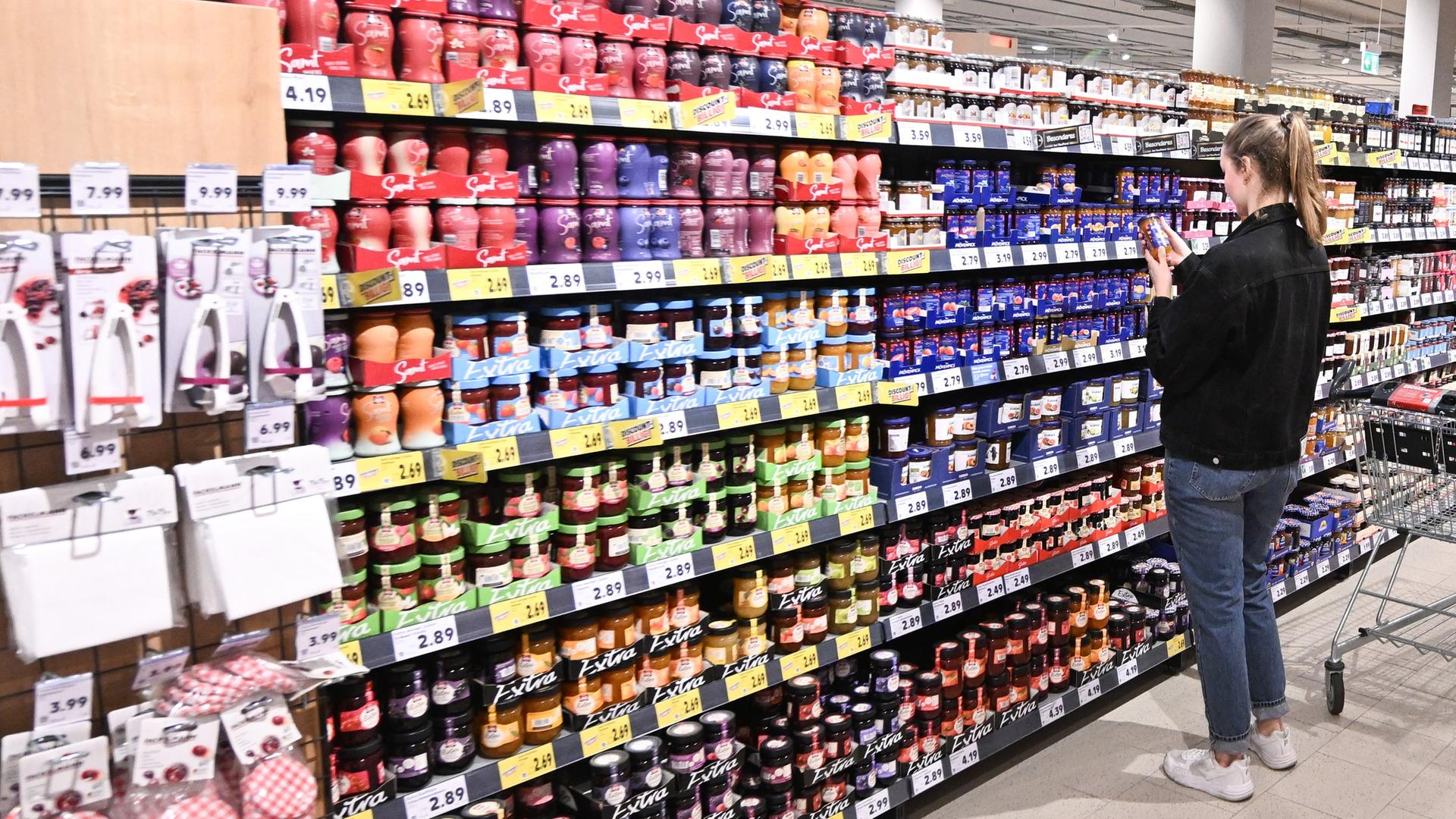 Eine Frau steht vor einem Regal mit Marmeladen und Aufstrich im Supermarkt. | dpa