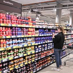 Eine Frau steht vor einem Regal mit Marmeladen und Aufstrich im Supermarkt.