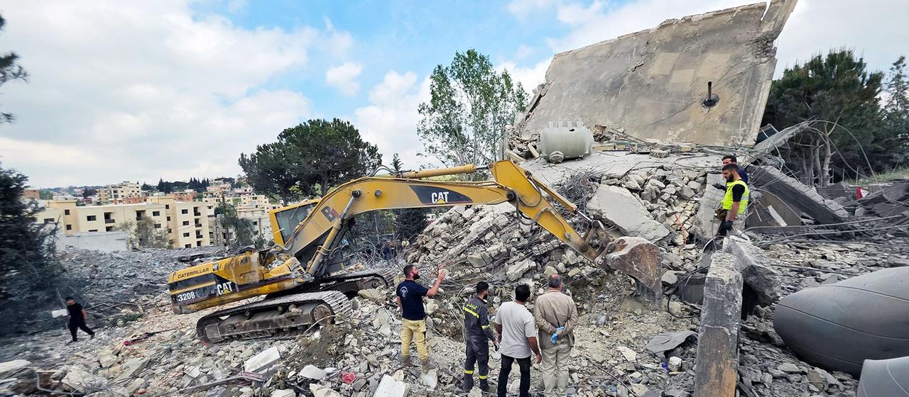 People stand in rubble in Nabatieh, Lebanon