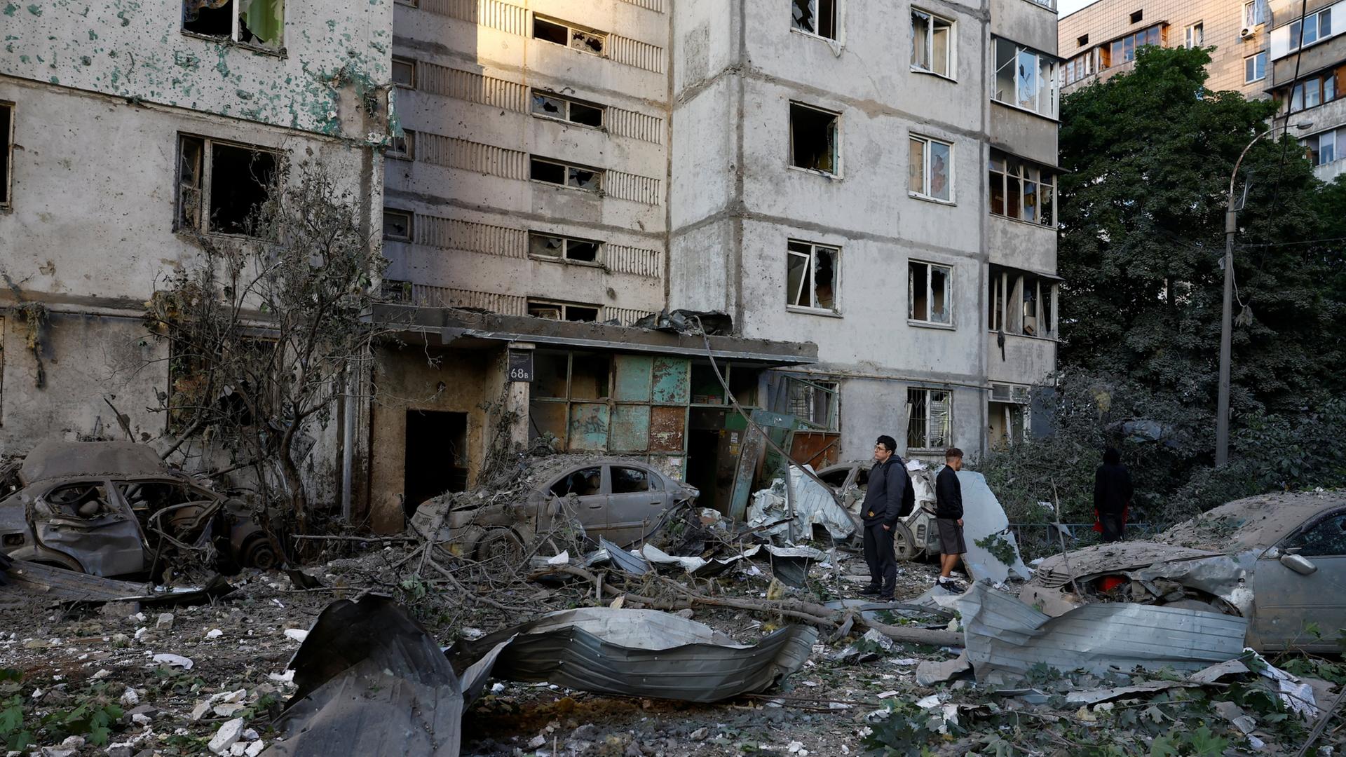 Menschen stehen vor einem durch Luftangriffe verwüsteten Eingangsbereich eines Hauses in Kiew. | REUTERS/Valentyn Ogirenko