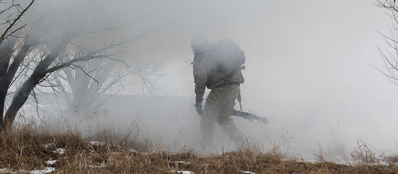 Ein ukrainischer Soldat läuft an einem unbekannten Ort in der Region Saporischschja durch Rauchschwaden.