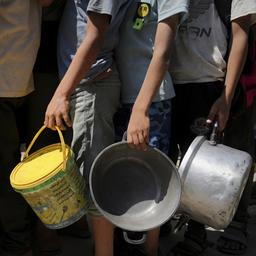 Menschen warten an einer mit Töpfen an einer Hilfsküche auf Essensspenden, Gaza