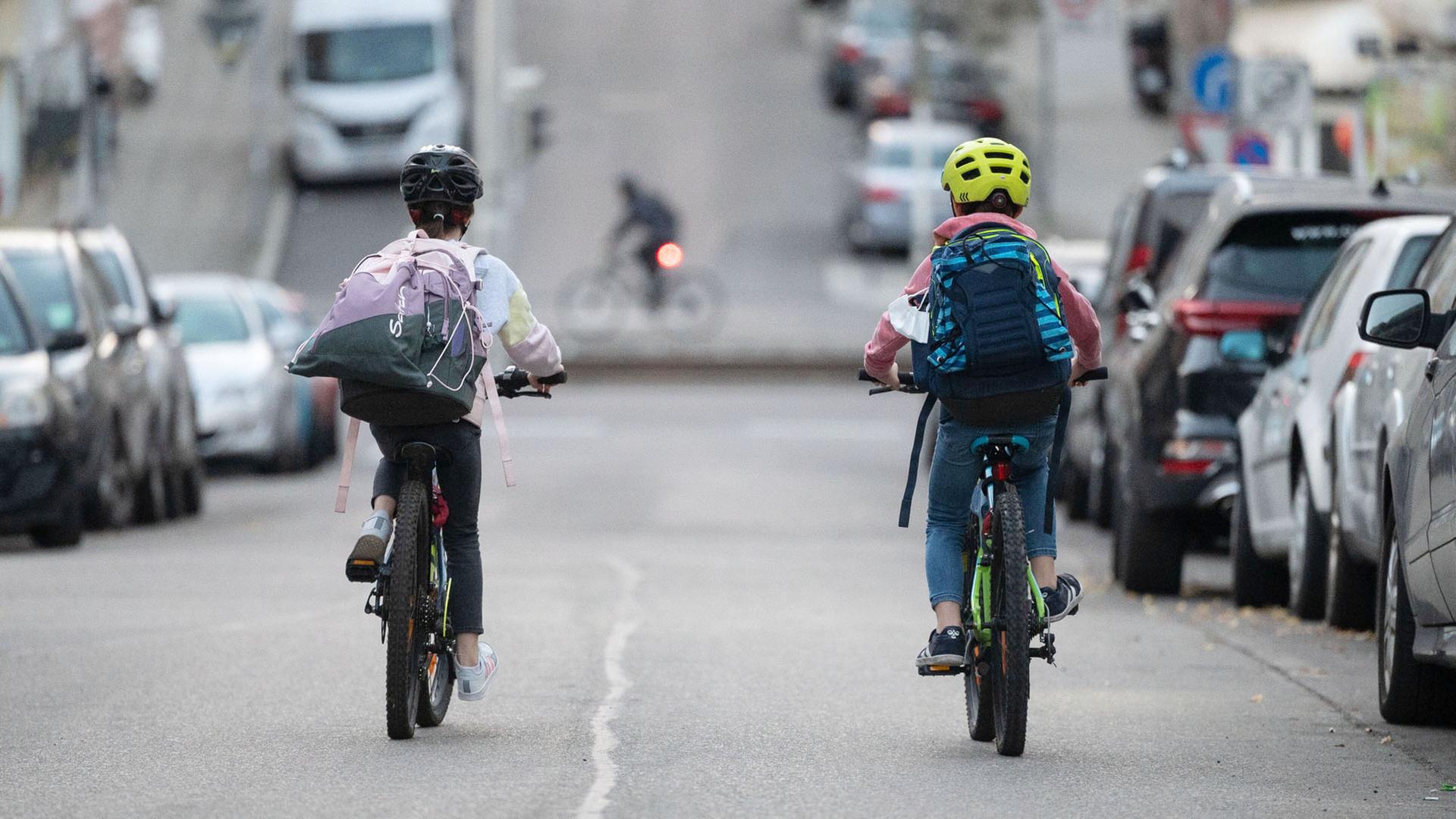 Zwei Schulkinder fahren mit ihren Fahrrädern eine Straße entlang. | picture alliance/dpa