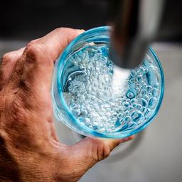 Jemand füllt ein Glas am Wasserhahn