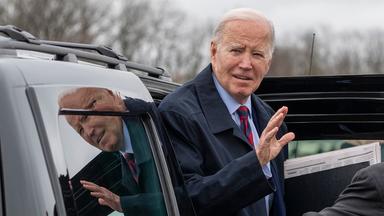 Joe Biden steigt aus einem Auto und winkt vorsichtig